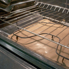 Interior of oven with oven liner spread across the bottom of oven, underneath oven heating element.