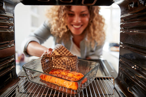 woman with curly hair reaching into modern oven