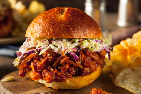 Pulled pork sandwich with a generous heap of coleslaw in a bun.