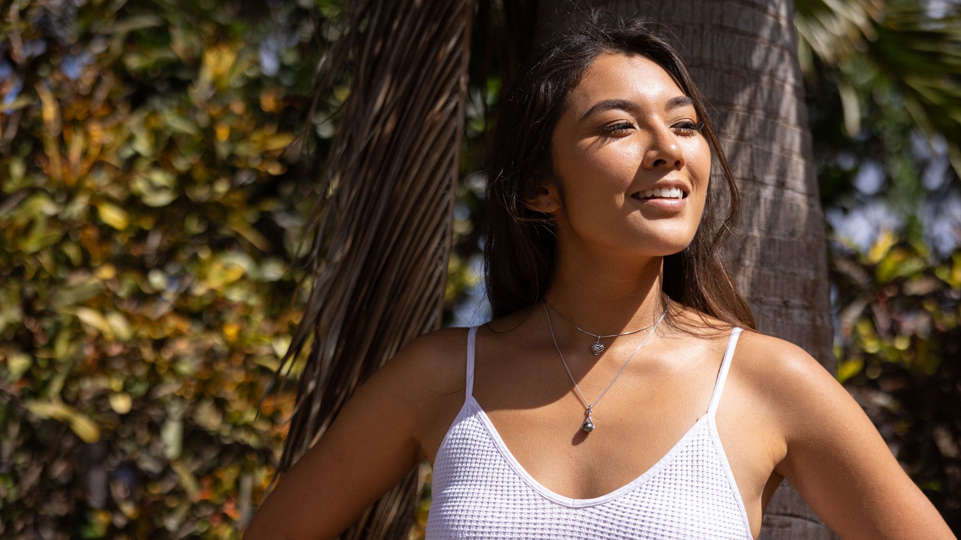 Model layering two necklaces