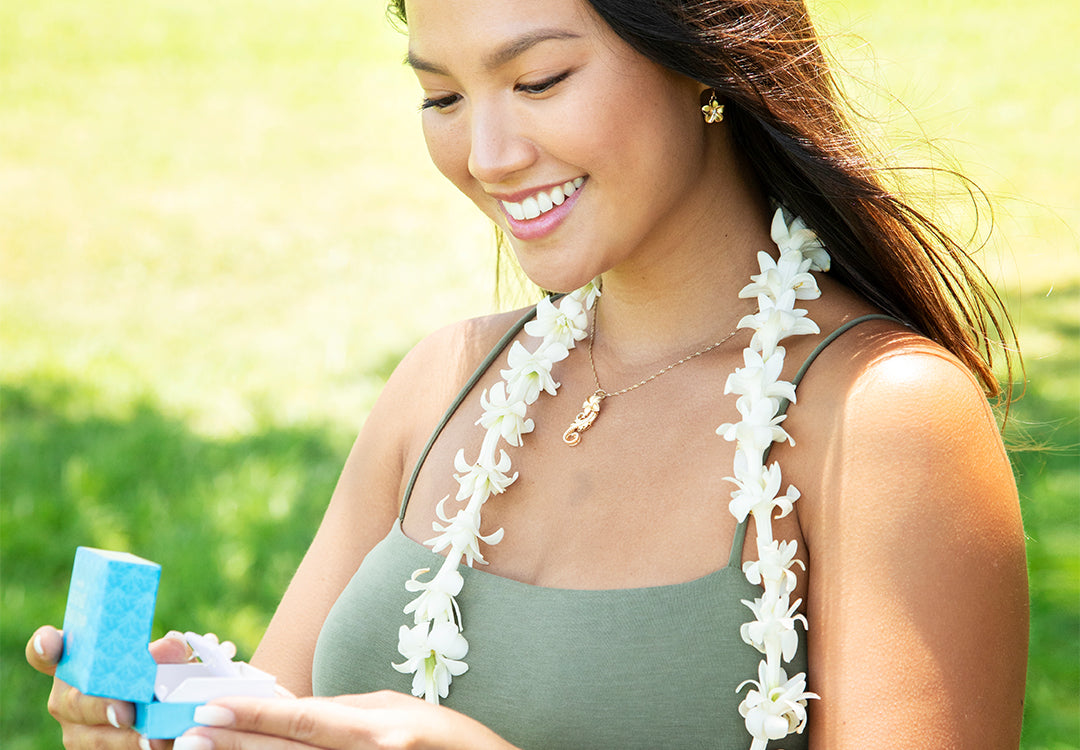 Modell trägt Lei, Plumeria-Ohrringe und hawaiianisches Erbstück Plumeria Scroll-Anhänger mit Maui Divers Jewellery Blue Box