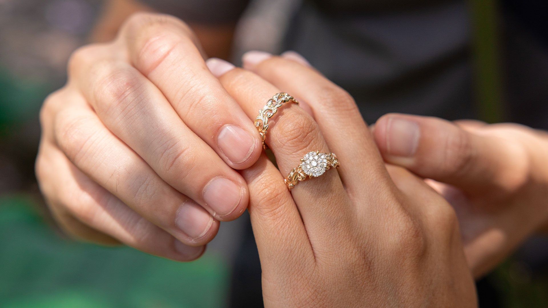 A man adding an wedding ring to a woman's hand with an engagement ring