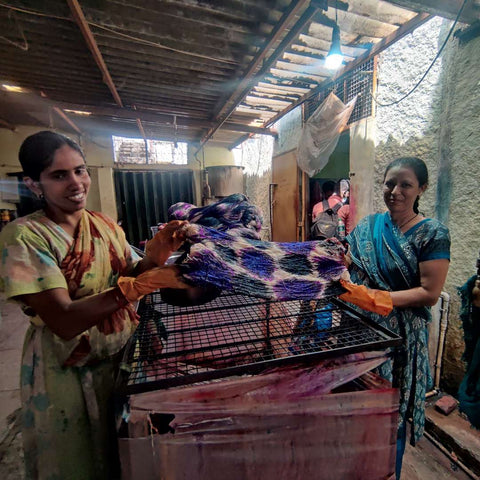 Two artisans in India are dying yarn by hand. 