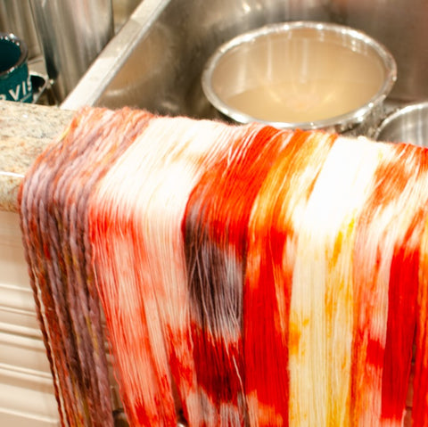 A few different skeins of freshly dyed yarn is drying over a counter top