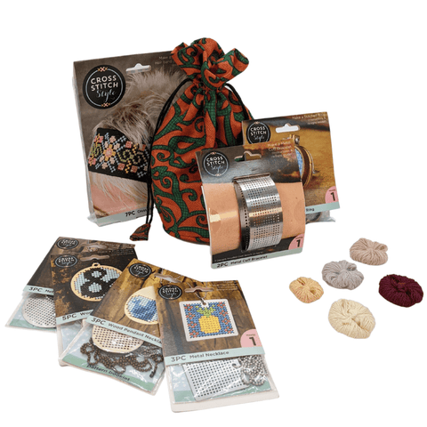 Stocking stuffer cross stitch kit wrap around me bundle with all items showing in front of a white background. Cross stitch headband, metal cuff bracelet, ring, circular metal necklace, square metal necklace, egg shaped wood necklace, bundles of thread, and bag that items are packed in.