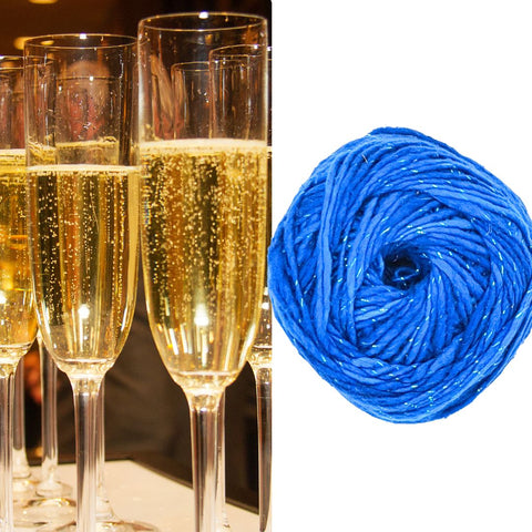 Flutes of golden champagne on the left, while a cake of sparkling blue worsted weight silk yarn on the right.