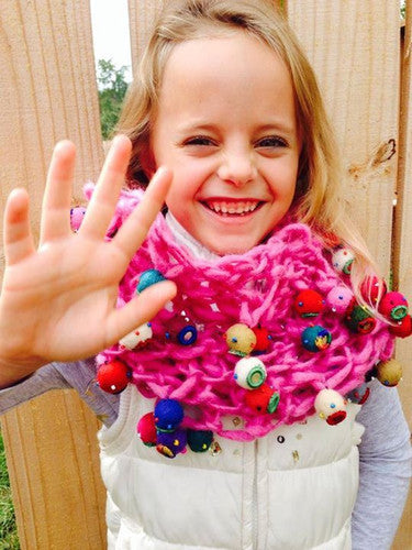 girl smiling wearing an arm knit scarf