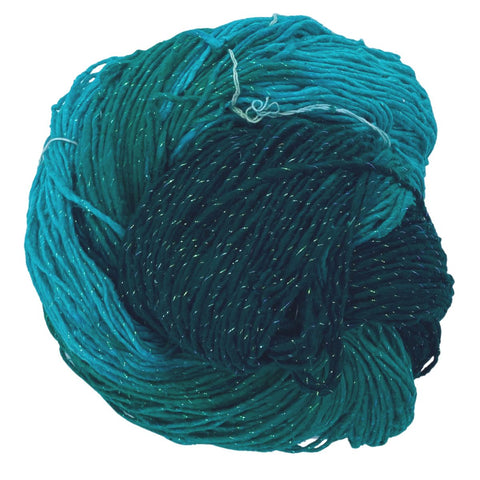 A closeup image of a cake of mint and dark teal sparkle worsted weight silk yarn on a white background.