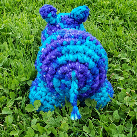 Blue crochet baby hippo sitting on grass