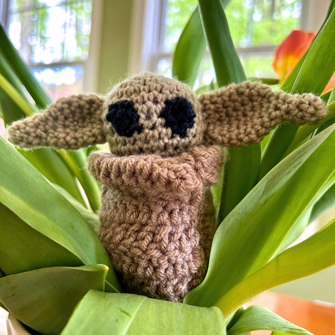 A finished intergalactic alien Amigurumi sitting in a plant