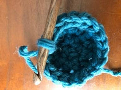 Using circular cast on and pulling tight with teal yarn and wooden crochet hook