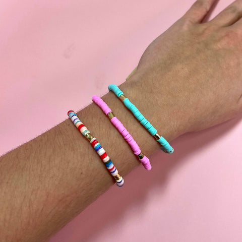 An arm is wearing three stackable Carnival Seed Bead Bracelets in multiple pastel colors.
