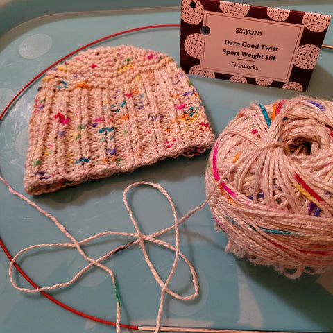 A white hat with multicolored speckles, made by Christa B