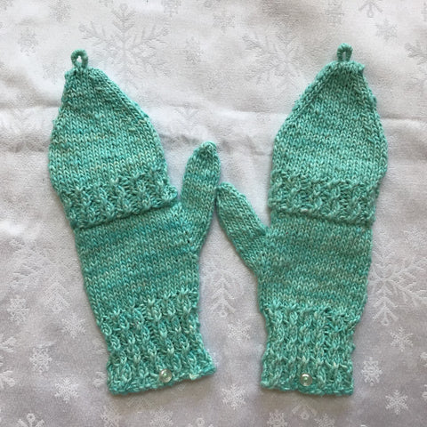 Finished knit mittens in teal on white tablecloth