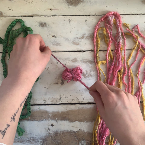 Tying loops of banana fiber yarn with another color of banana fiber yarn