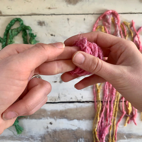 Carefully removing loops of banana fiber yarn from index and middle fingers to set aside