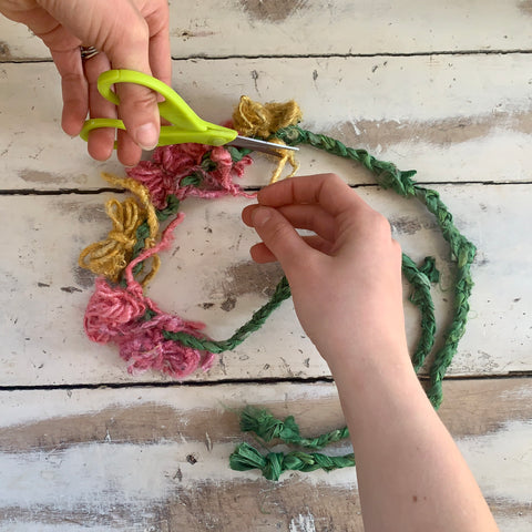 Trimming excess lengths of banana fiber yarn from flowers