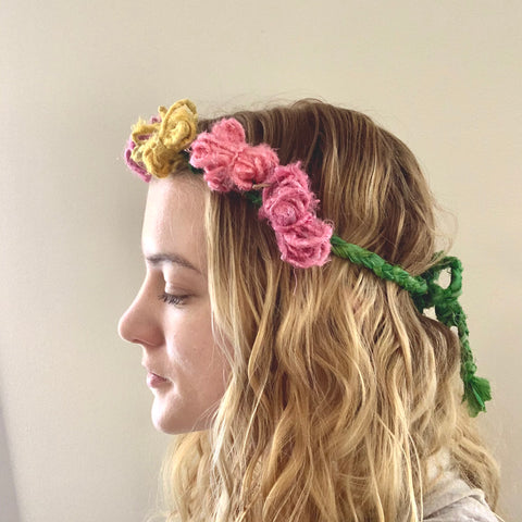 Model wearing green, yellow, and pink flower crown in front of a beige background