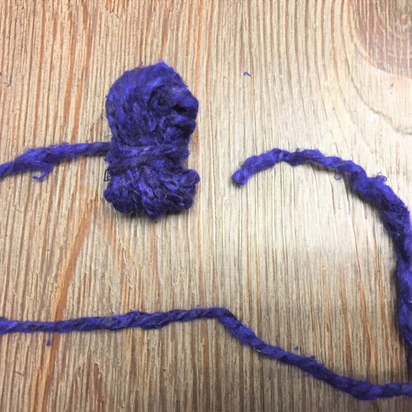 Purple yarn ball on a wooden surface