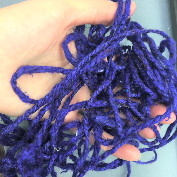 Woman's hand holding tangled purple yarn