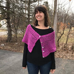 A front facing view of a woman wearing purple pink shawl wrap with trees in the background