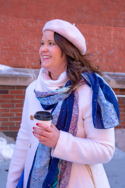 Woman wearing sari silk medley scarf with a winter coat in front of a brick wall