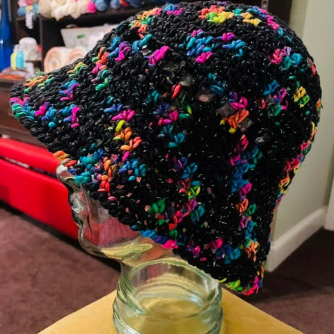 A black hat with multicolored patches is modeled on a clear mannequin head