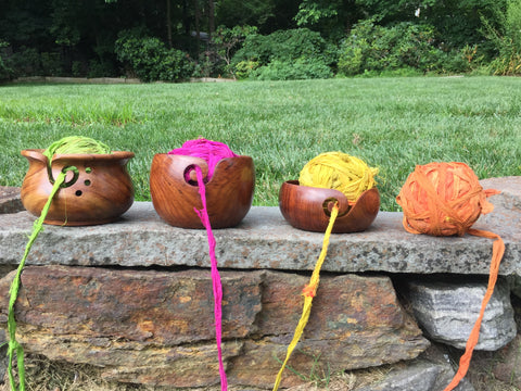 Multicolored Sari ribbon yarn in yarn bowls outside on a stone wall with greenery in the background.