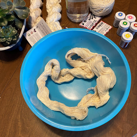 a loose skein of yarn sits in a blue bowl, ready to soak.