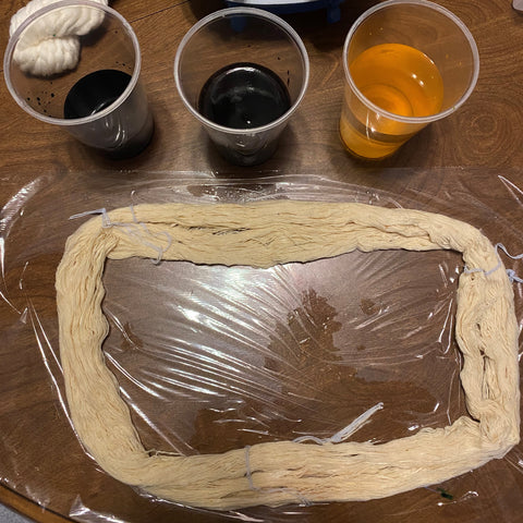 A damp loose skein of yarn is laid out over plastic wrap, ready to be dyed.