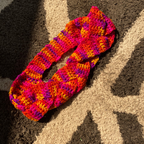 The finished braided headband is laying in the sun on a white and grey geometric rug.