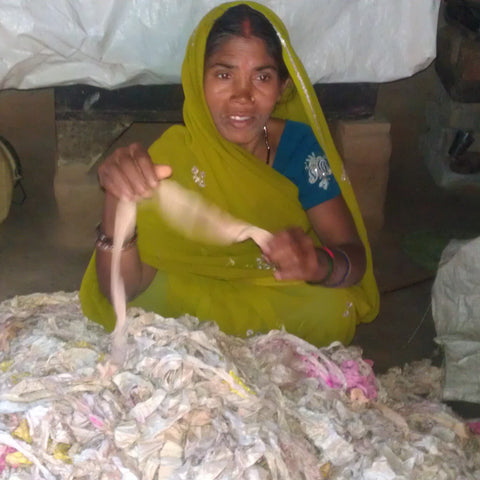 Artisans sort through torn sari fabric before it is made intoribbon yarn