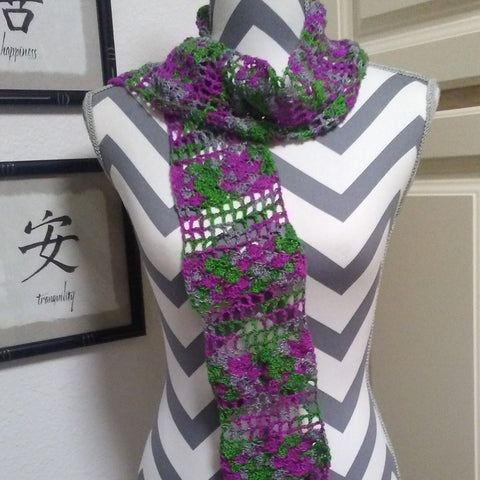 A white and grey chevron mannequin has a green and purple scarf wrapped around it's neck. 