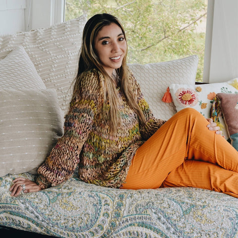 side view of a woman with long hair wearing knit sweater made from recycled chiffon ribbon yarn.