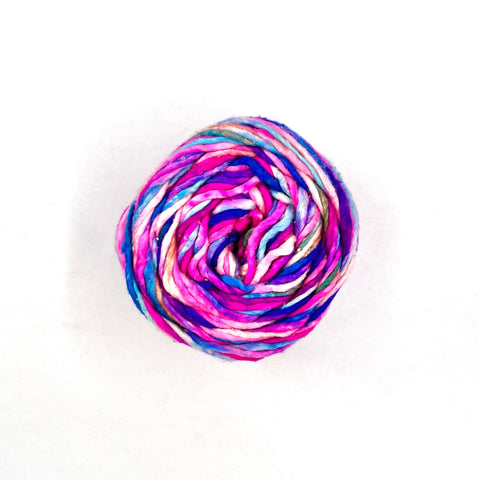 A single skein of worsted weight silk yarn, phenomena, which is white, pink, purple, and blue.