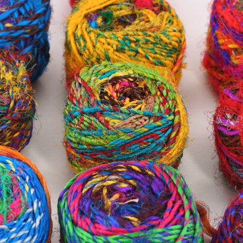 Multiple cakes of multicolored spice market yarn are resting on a white background.
