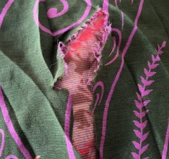 A picture of a green and pink skirt with a 5 inch tear in the fabric.