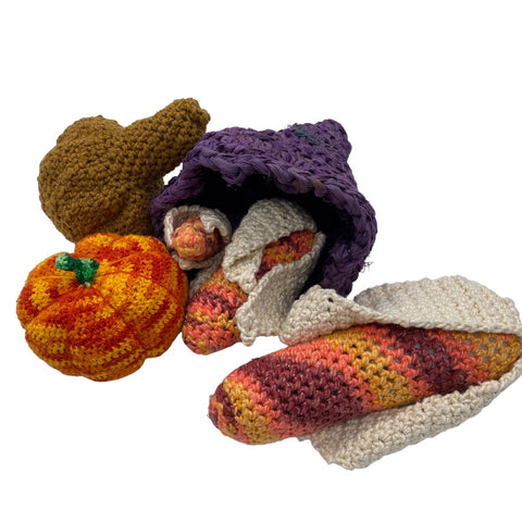 A purple cornucopia on a white background, stuffed with crochet corn, pumpkins, and gourds.