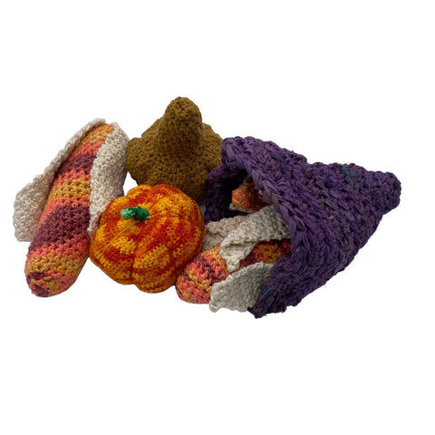 A purple cornucopia on a white background, stuffed with crochet corn, pumpkins, and gourds.