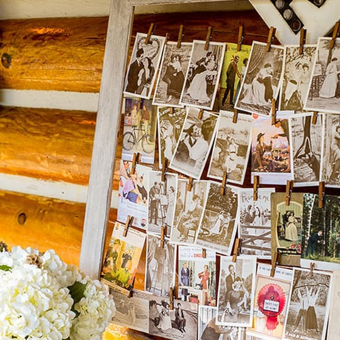 Against a wooden wall, a frame of photos are pinned to strands of string with wooden clothespins 