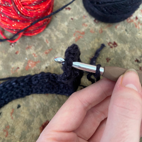 An image showing how to slip stitch the black yarn to the side of the headband