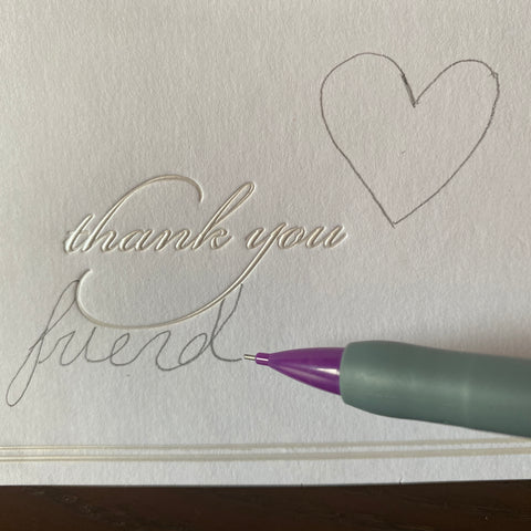 An upclose image of a white thank you card being written on by a purple mechanical pencil