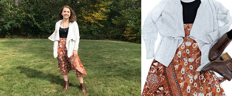 women wearing floral sari midi skirt with a beige cardigan and black tank top. turqoise necklace and brown booties standing in grass