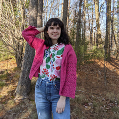 a person wearing a pink cardigan outside