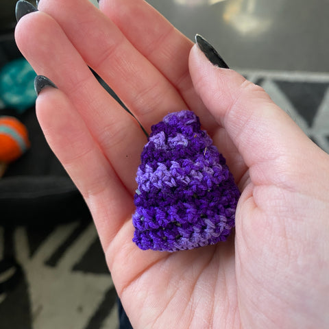 A hand holding a little pouch made out of ombre silk yarn and stuffed with dried lavender.