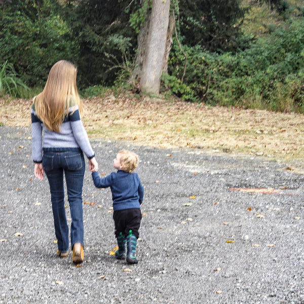 Back view of woman and child walking down a paved road