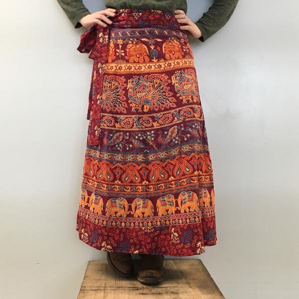 Woman standing on a wooden box in front of a white background wearing a red cotton patterned maxi skirt