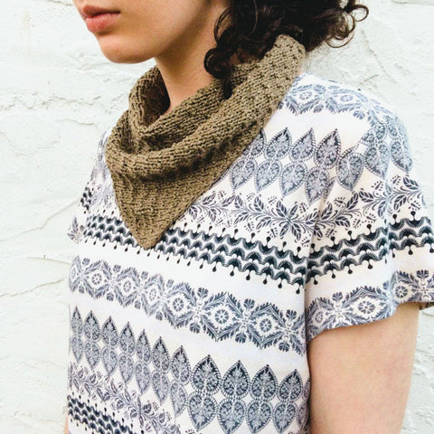 Woman wearing white and black geometric patterned sweater wearing a dark green naturally dyed hand-knit Poppyseed Scarf