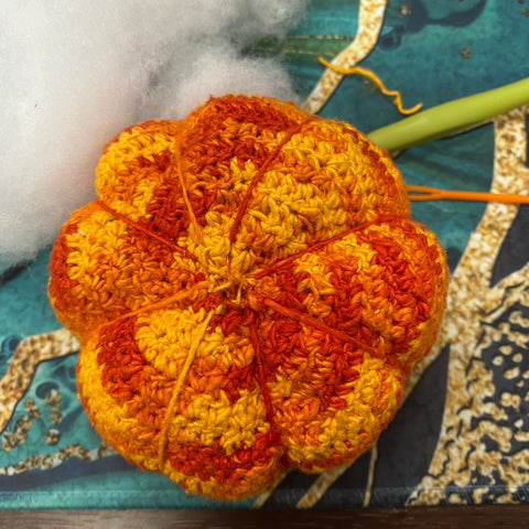 The bottom of the orange ombre crochet amigurumi pumpkin, showing the drawstring and parting effect for round 16 and 17