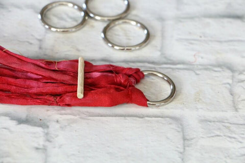 4 metal rings and red yarn sitting on a white surface
